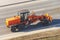 Orange grader tractor driving on city highway