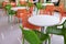 Orange and green chairs around white tables. A modern interior of food court in a mall, cafe, airport or family fast food