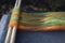Orange and green wool roving on a blending board with two wooden dowels