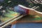 Orange and green wool roving on a blending board with two wooden dowels and a wire brush