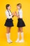 Orange is the healthiest fluid. Little girls drinking juice from orange fruits on yellow background. Small