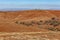 Orange hills and scarce vegetation landscape.