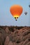 Orange Hot Air Balloon Flying In Sky Above Rocks In Nature