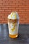 Orange iced coffee latte in glass on wooden table