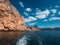 Orange island mountain coastline, blue sky with clouds and ocean water, view from boat, summer travel landscape