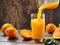 Orange juice being poured into a glass with fresh fruit on wooden background