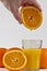 Orange juice dripping into glass from orange fruit