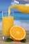 Orange juice pouring into glass on the beach