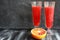 Orange juice in shabby looking glasses and half oranges on dark table