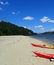 Orange kayaks on the sand on shore of river