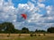 Orange kite on the cloudy sky and field background