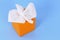 Orange kleenex style tissue box, white soft tissues, blue background, copy space