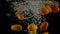 Orange kumquats fall under water super slow motion video. Dark background