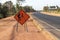 Orange label with pictograms survey engineering inside placed along the road under construction.