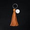 Orange Leather Tassel key ring on black wooden background. Fashion leather key chain for decoration