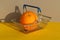 Orange lies in a shopping basket on gray and yellow backgrounds