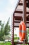 The orange life buoy hangs at the wooden station