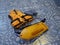 An orange life jacket, gray small rubber flippers, and an orange plastic rescue torpedo buoy for the lifeguard on the