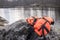 Orange life jacket lies on the rocky shore of the lake in the ba