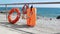 Orange life jacket and lifebuoy on the beach by the sea. Safety equipment for rescuing people on the seashore