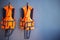 Orange life jackets hanged on plain grey wall by swimming pool for emergency