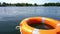 Orange life rescue buoy floating on lake water far from coast. Gimbal motion