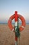 Orange life saver ring with green rope on wooden post. Sandy beach, Corralejo, Fuerteventura at sunrise.