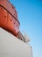 Orange lifeboat anchored on board of a ship against blue sky