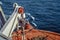 An orange lifeboat hanging from the side of a cruise