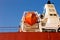 Orange lifeboat at tail of international cargo ship in the ocean for emergency evacuation loading for safety, Freight