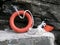 Orange lifebuoy abandoned on the rocks by a boat