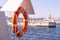 Orange lifebuoy on beach by sea. Safety equipment for rescuing people on seashore. Orange lifebuoy on the pier of blue