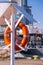 Orange lifebuoy on beach by sea. Safety equipment for rescuing people on seashore. Orange lifebuoy on the pier of blue