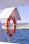 Orange lifebuoy on beach by sea. Safety equipment for rescuing people on seashore. Orange lifebuoy on the pier of blue