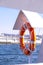 Orange lifebuoy on beach by sea. Safety equipment for rescuing people on seashore. Orange lifebuoy on the pier of blue