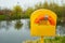 Orange lifebuoy in box at the edge of the pond.