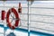 Orange lifebuoy emergency gear/ device/ equipment with reflective silver strips on cruise ship deck.