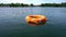 Orange lifebuoy floating on lake water far away from shore. Gimbal motion