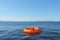 Orange lifebuoy floating in open ocean. Copy space