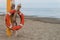 Orange lifebuoy hanging on a dry dead trunk on a beach