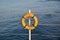 An orange lifebuoy hanging from rope handrails at the marina