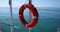 Orange lifebuoy hangs from pole on dock