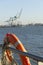 Orange lifebuoy in the harbor with cranes