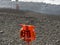 Orange lifebuoy and life jacket hang on the pebble beach of the foamy sea