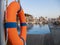 Orange lifebuoy near public swimming pool On a blurred background, a swimming pool is visible