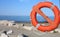 Orange lifebuoy for people near rocks at the sea in summer