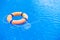 Orange lifebuoy pool ring float on blue water. Life ring in swimming pool, life ring floating on top of sunny blue water