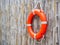 An orange lifebuoy, safety ring hanging on bamboo fence wall background.