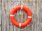 An orange lifebuoy, safety ring hanging on bamboo fence wall background.