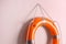 Orange lifebuoy and space for text on pink background. Rescue equipment